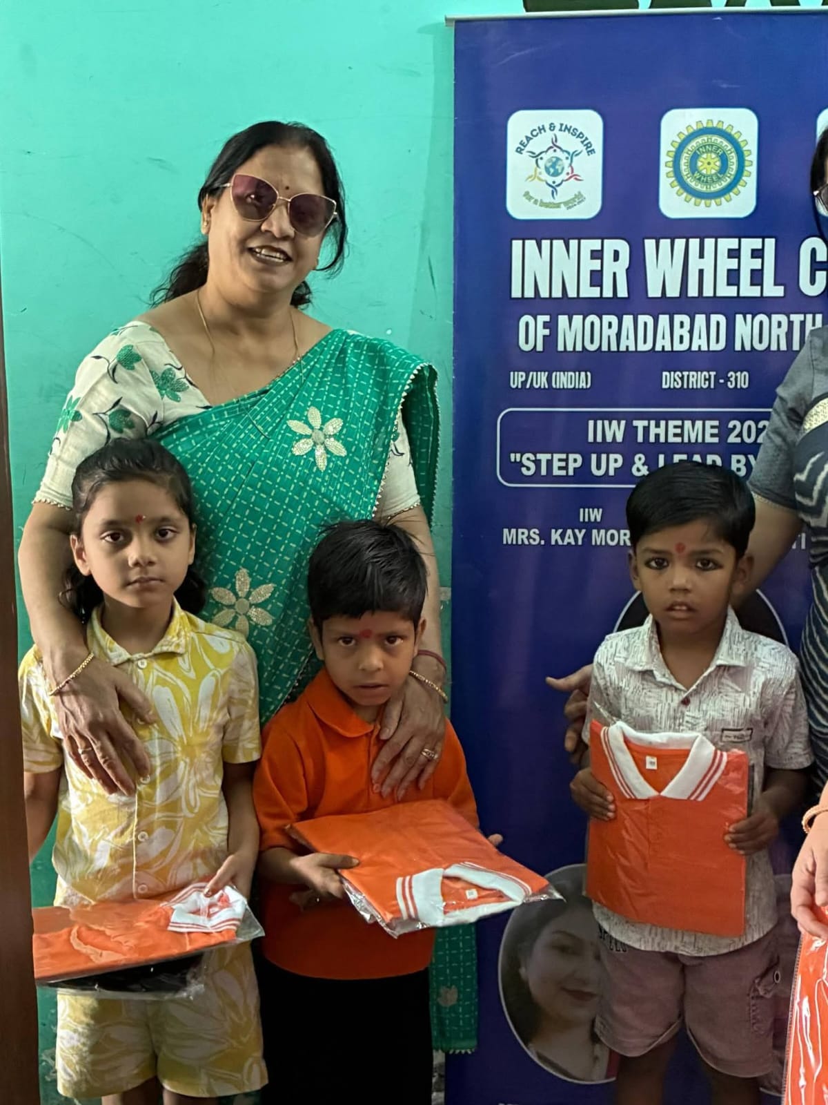 Children being distributed their new orange and white school uniforms